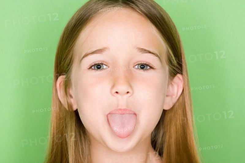 Studio portrait of teenage (16-17) girl sticking out tongue. Photo : Rob Lewine
