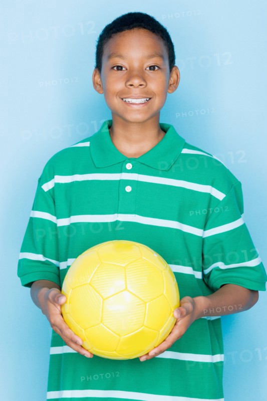 Studio portrait of teenage boy holding ball. Photo : Rob Lewine