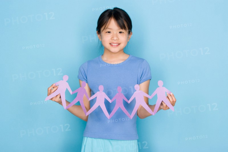 Studio shot portrait of teenage girl holding paper chain, waist up. Photo : Rob Lewine