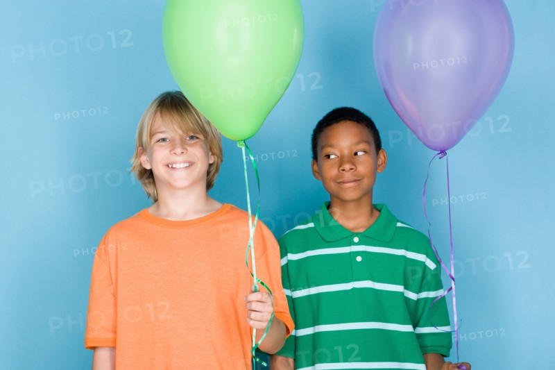 Studio shot portrait of two teenagers with balloons, head and shoulders. Photo : Rob Lewine