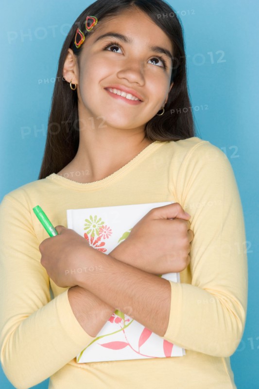 Studio shot portrait of teenage girl holding notebook, waist up. Photo : Rob Lewine