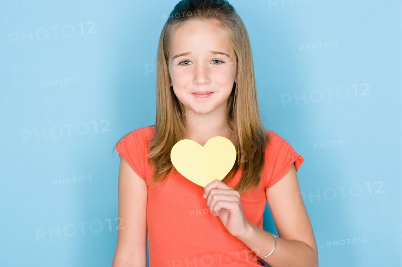 Studio shot portrait of teenage girl holding hart, head and shoulders. Photo : Rob Lewine