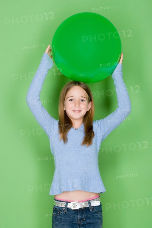 Studio shot portrait of teenage girl holding ball on her head, waist up. Photo : Rob Lewine