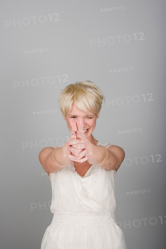 Studio shot portrait of mid adult woman aiming in viewer's side, waist up. Photo : Rob Lewine