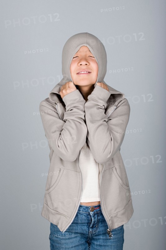 Studio shot portrait of teenage girl in hooded shirt, waist up. Photo : Rob Lewine
