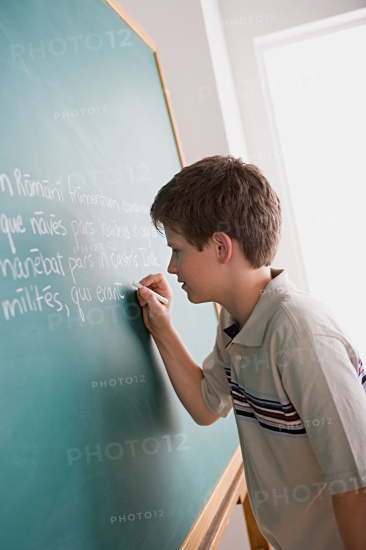 Boy writing on blackboard. Photo : Rob Lewine