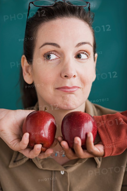 Teacher being offered tow apples by pupils. Photo : Rob Lewine