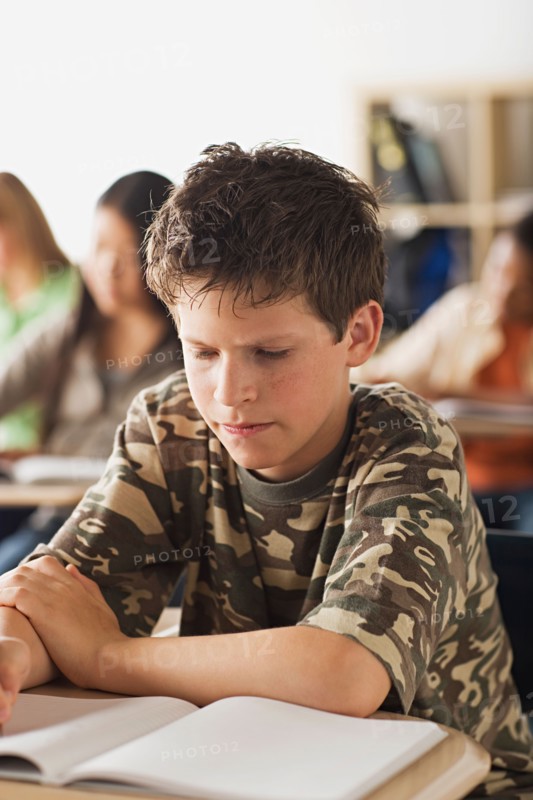 Serious schoolboy sitting in classroom. Photo : Rob Lewine