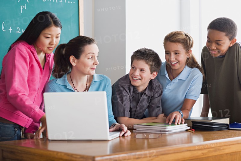 Group of school children with teacher using laptop . Photo : Rob Lewine