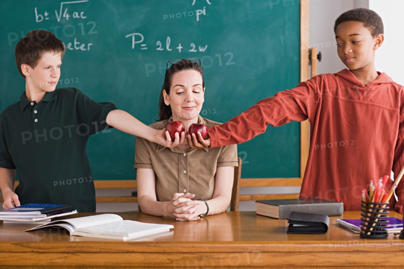 Two boys holding apples in front of teacher. Photo : Rob Lewine