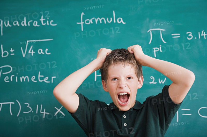 Frustrated schoolboy in front of blackboard. Photo : Rob Lewine