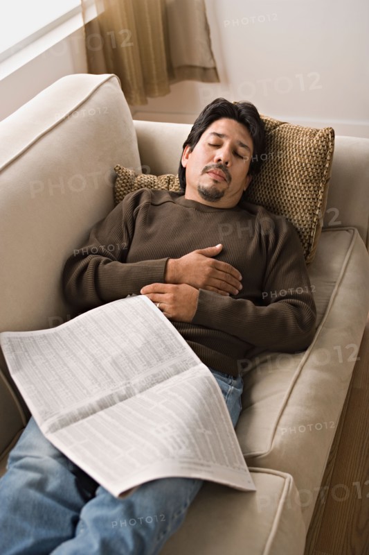 Mature man sleeping on sofa with newspaper. Photo : Rob Lewine