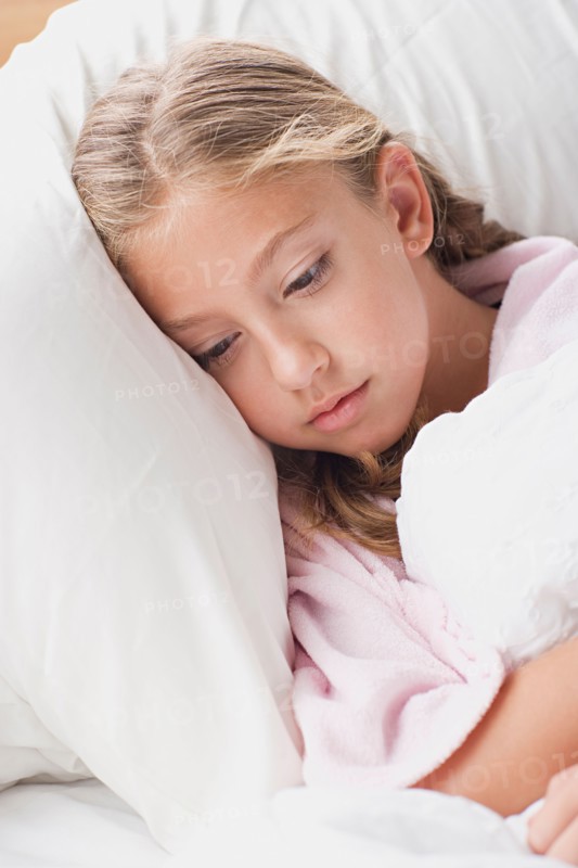 Portrait of girl laying in bed. Photo : Rob Lewine