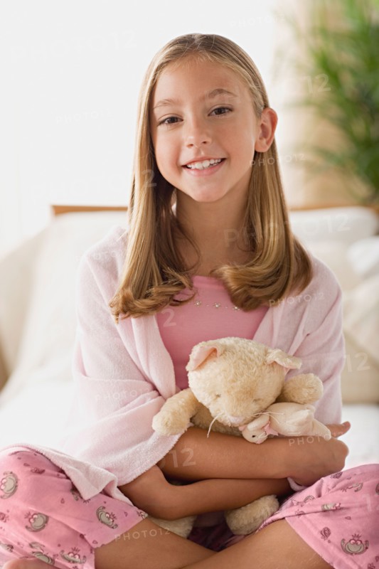 Smiling girl (12-13) holding teddy bear. Photo : Rob Lewine