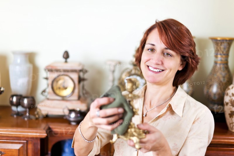 Smiling woman holding old candlestick . Photo :  Elena Elisseeva