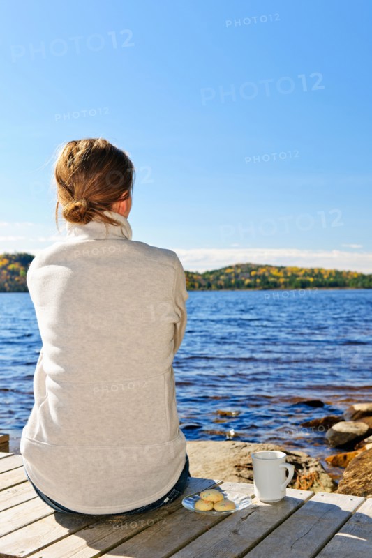 Canada, Ontario, Algonquin Park, Teenage girl sitting on pier and looking at lake. Photo :  Elena Elisseeva