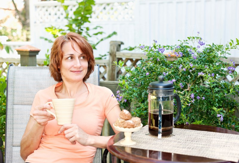 Woman having coffee in garden. Photo : Elena Elisseeva