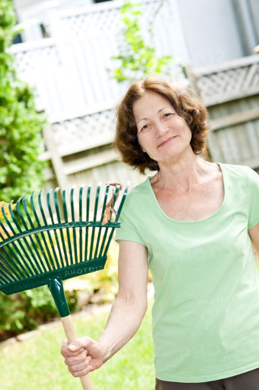 Senior woman with rake in garden. Photo : Elena Elisseeva