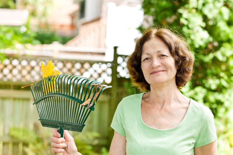 Senior woman with rake in garden. Photo : Elena Elisseeva