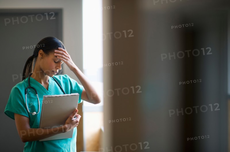 Female nurse with head in hands.