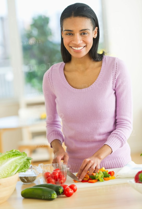 Portrait of woman chopping vegetables in kitchen.