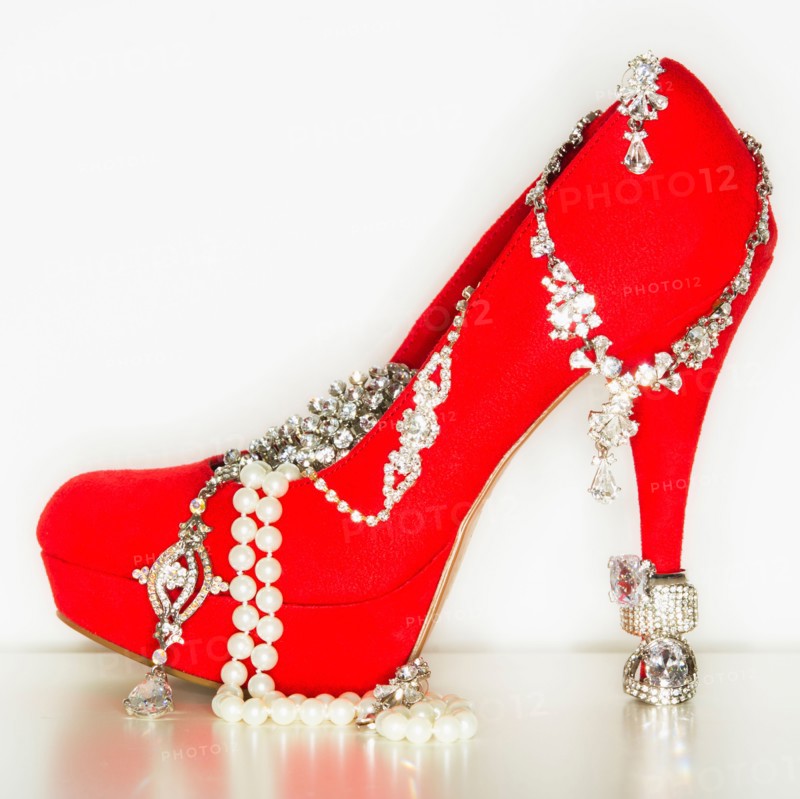 Studio shot of red stiletto with jewelry.