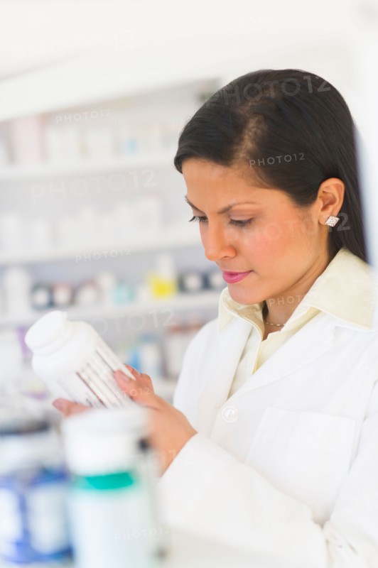 Pharmacist reading label on medicine bottle.
