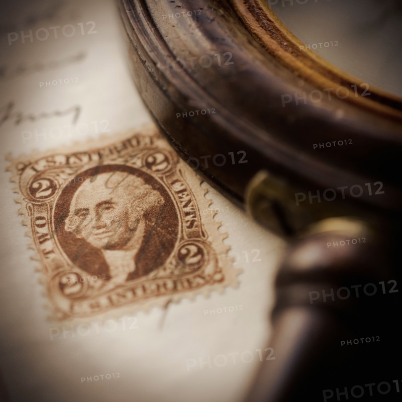Studio shot of magnifying glass and old post stamp.
