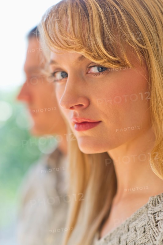 Close up woman's face with man in background.