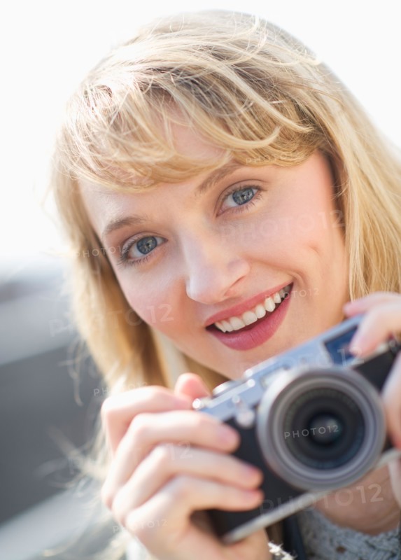 Portrait of smiling woman with camera.