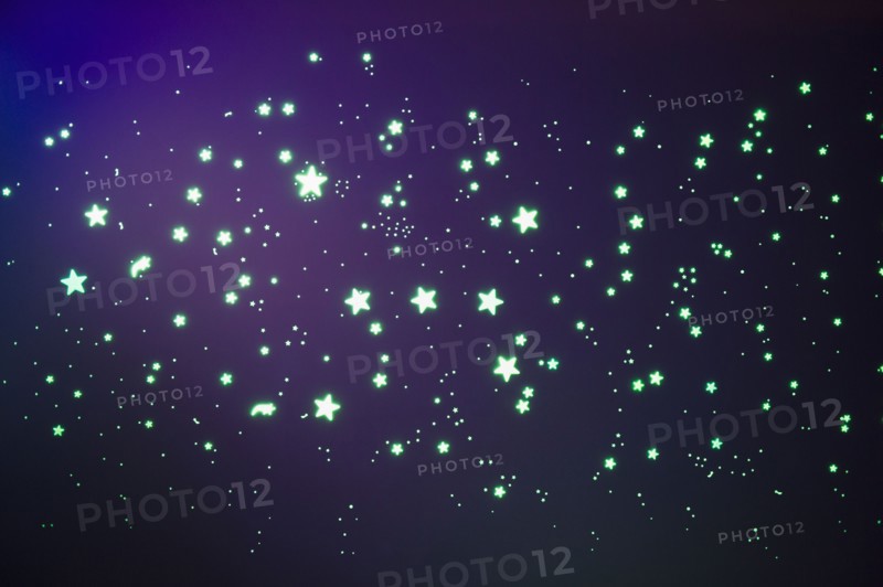 Fluorescent stars on blue background, studio shot. Photo : Jamie Grill