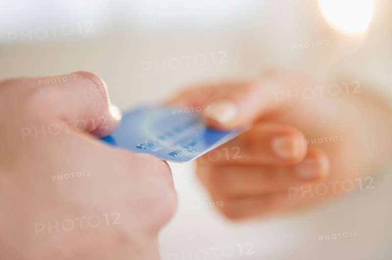 Close up of man's and woman's hands holding credit card. Photo : Jamie Grill