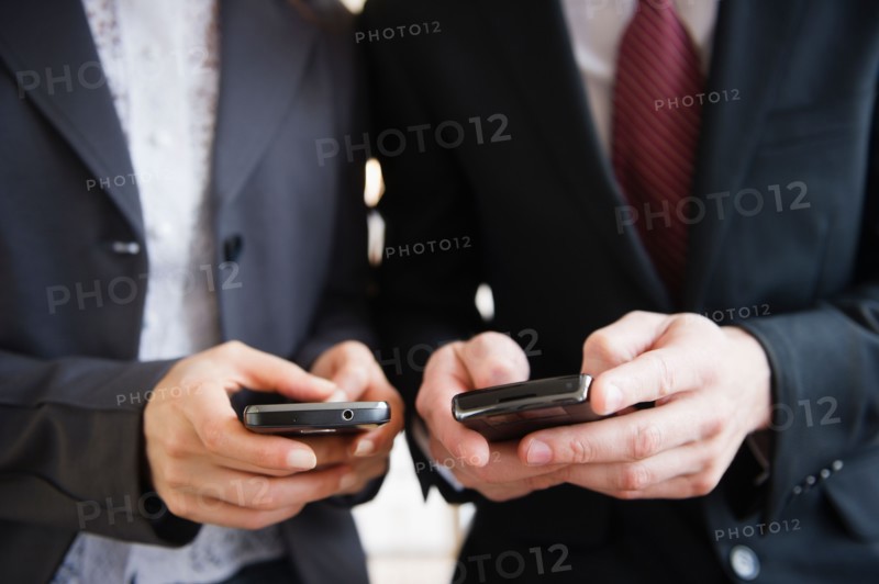 Close up of business people's hand texting on mobile phones. Photo : Jamie Grill