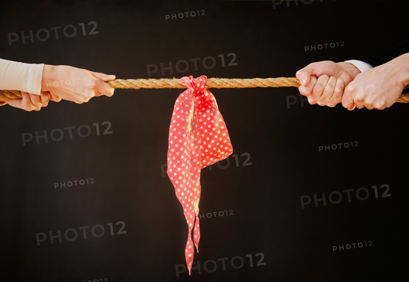 Close up of man's and woman's hands pulling rope, studio shot. Photo : Jamie Grill
