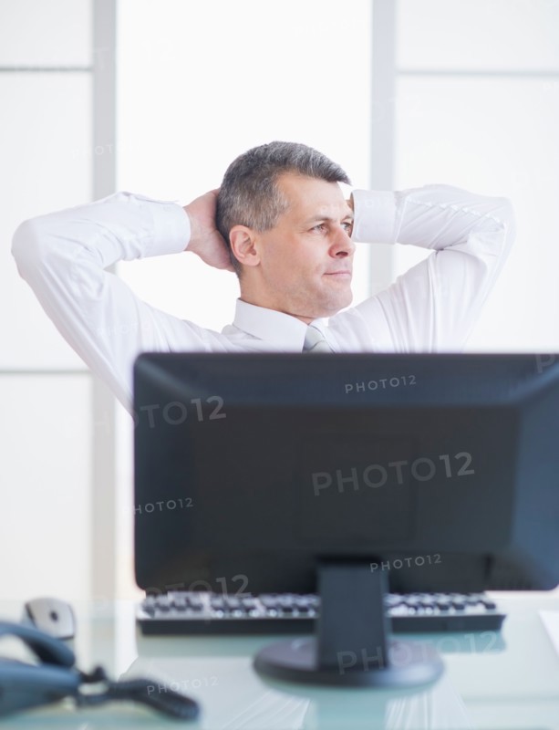 Portrait of businessman relaxing at desk. Photo : Daniel Grill