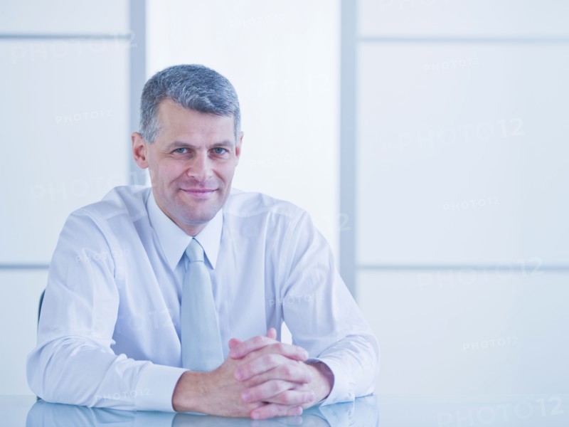 Portrait of businessman sitting at desk. Photo : Daniel Grill