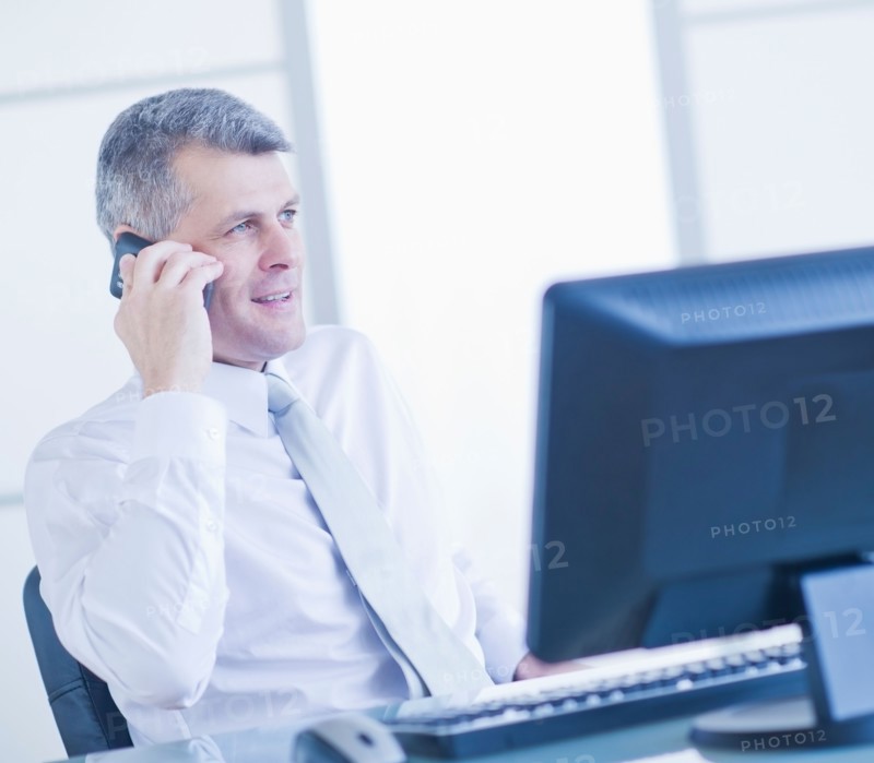 Man with mobile phone sitting in office. Photo : Daniel Grill