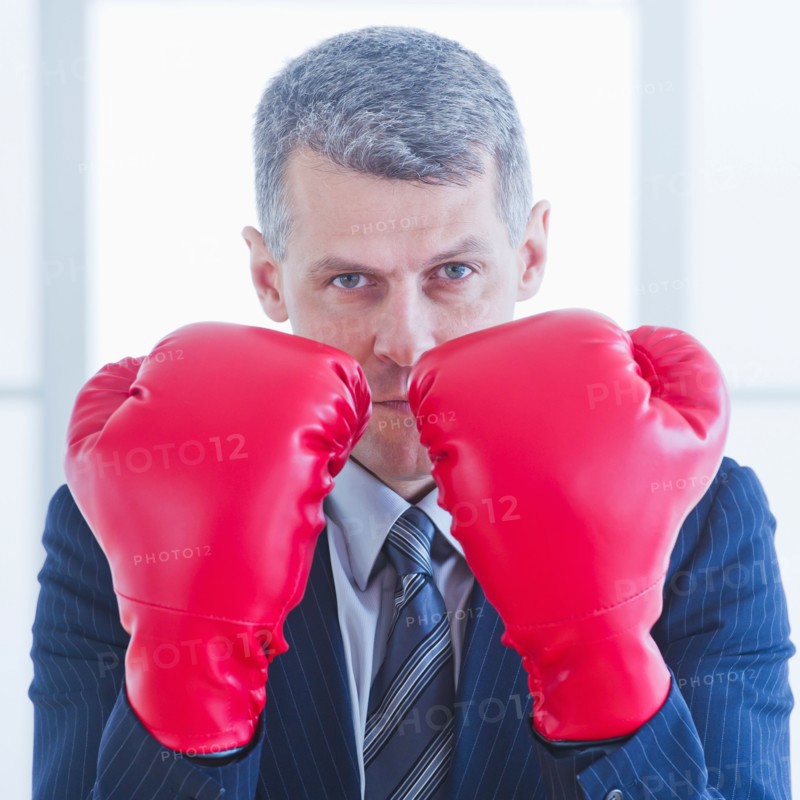 Businessman wearing red boxing gloves. Photo : Daniel Grill