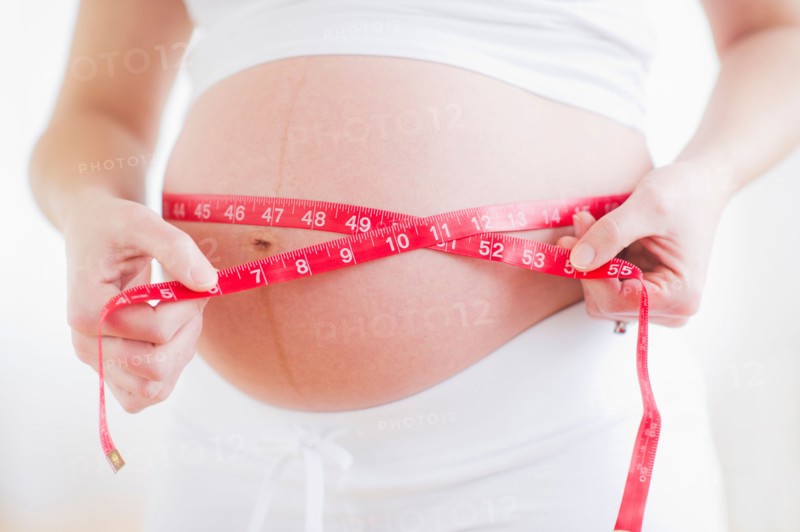 Pregnant woman measuring her belly. Photo : Daniel Grill