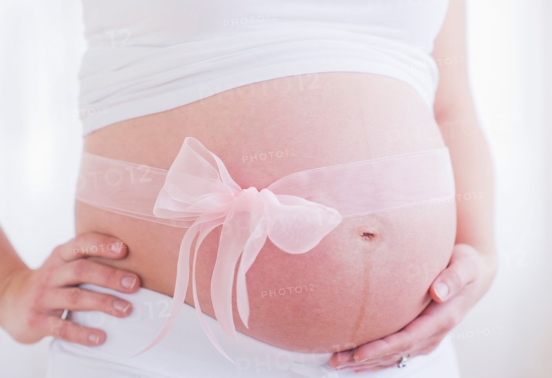 Pregnant woman with pink ribbon on her belly. Photo : Daniel Grill