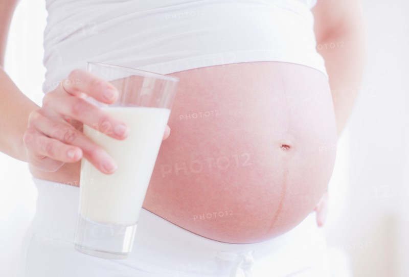 Pregnant woman with glass of milk. Photo : Daniel Grill