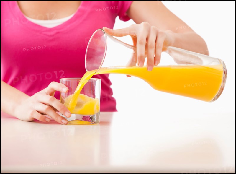 Young woman pouring juice into glass. Photo : Mike Kemp