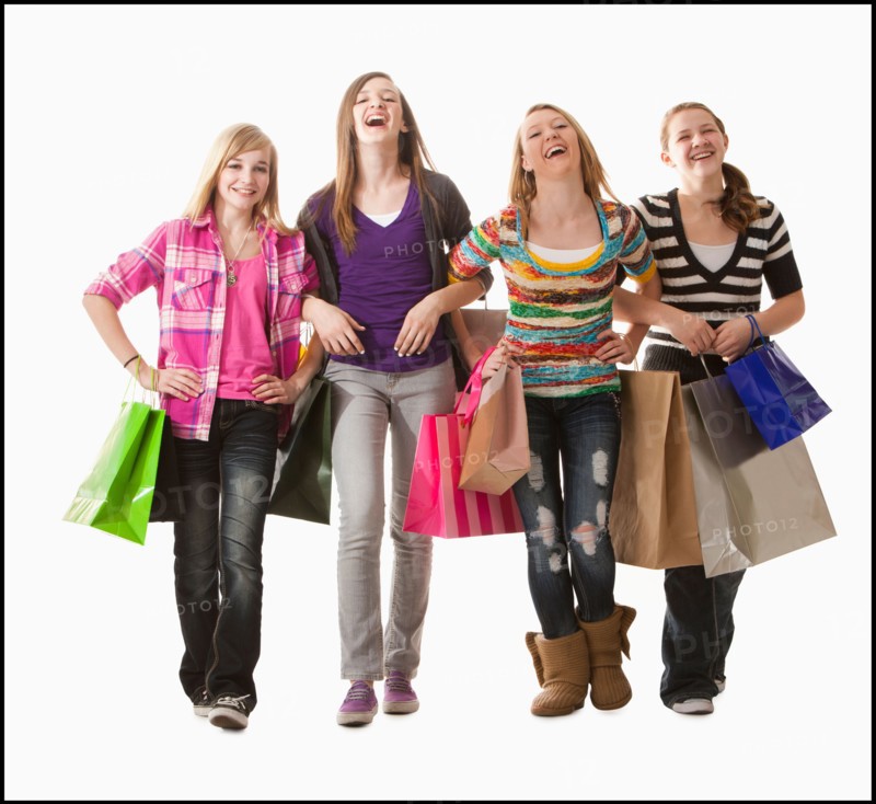 Studio shot of four happy girls (12-13) with shopping bags. Photo : Mike Kemp