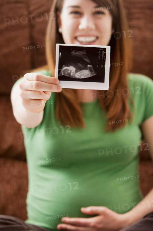 Portrait of pregnant woman showing ultrasonography scan. Photo : Mike Kemp