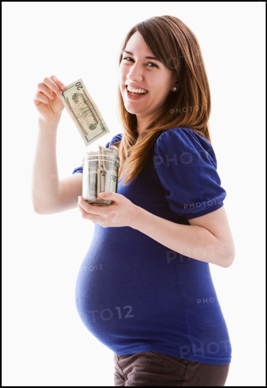 Studio Shot of woman holing baby jar with money. Photo : Mike Kemp