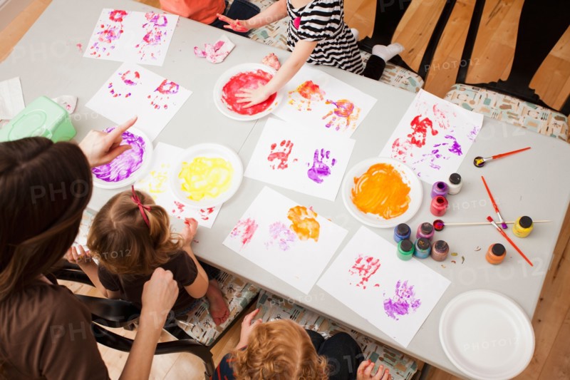 High angle view of children (2-3, 4-5) printing their hands on paper. Photo : Mike Kemp