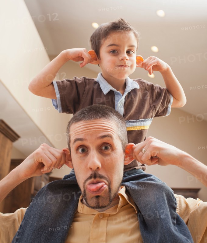 Father and son (6-7) pulling funny faces. Photo : Mike Kemp