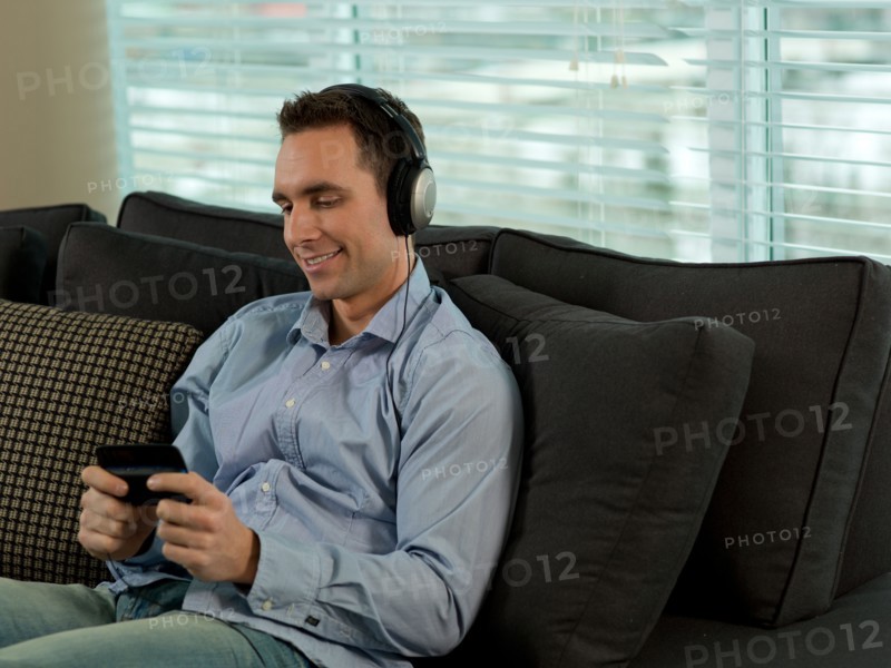 Man sitting on sofa listening music. Photo : Dan Bannister