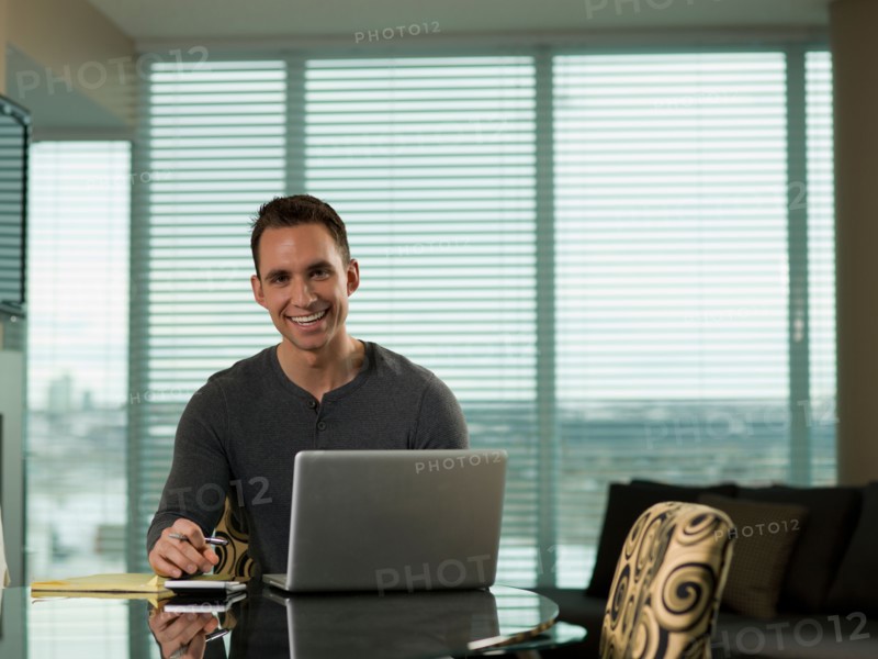 Young man paying bills at kitchen table. Photo : Dan Bannister