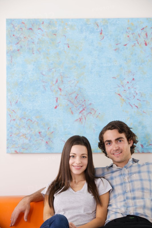 Portrait of young couple sitting on sofa. Photo : Rob Lewine